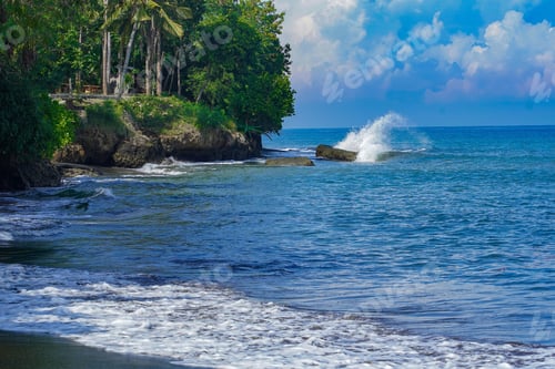 Preview: Closeup of a beautiful shoreline with rocky forested coast and water waves hitting them