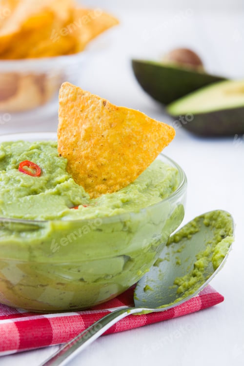 Preview: Delicious guacamole with tortilla chips and fresh avocado in background