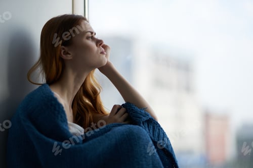 Preview: woman sitting on the windowsill and looking out the window dreamy kind of rest