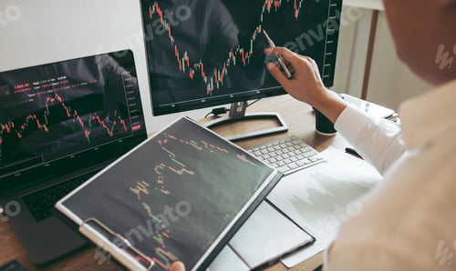 Preview: Investor man analyzing the graph of the stock market using a pen pointing to the computer screen.