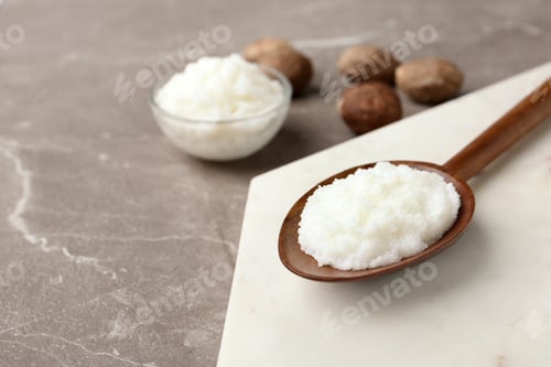 Preview: Shea butter in wooden spoon and bowl with nuts on grey background