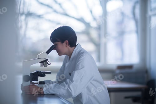Preview: Female chemist looking through a microscope