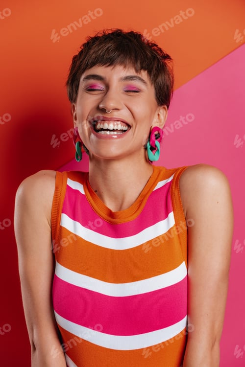 Preview: Attractive young woman looking excited while standing against colorful banners