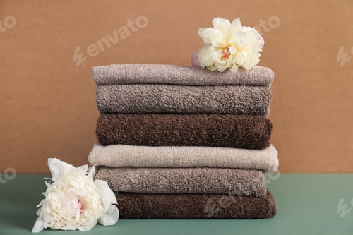 Preview: Stack of soft towels and peony flowers on color background