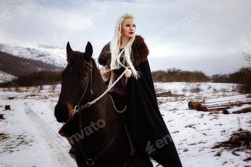 Preview: Woman viking with a black horse against the background of mountains