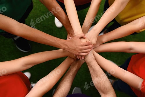 Preview: Group of volunteers joining hands together outdoors, top view