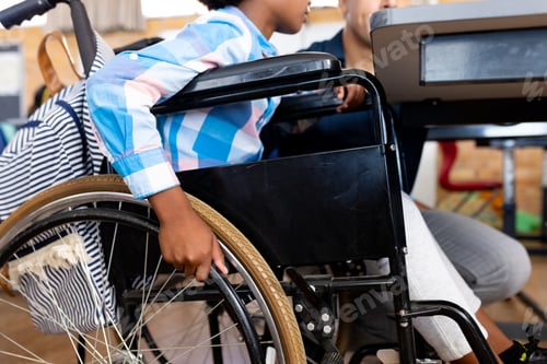 Visualização: Seção intermediária de diversos meninos em cadeira de rodas e professor do sexo masculino em sala de aula no ensino fundamental