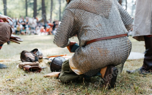 Preview: An ancient warrior in chain mail sitting on the grass, close-up, rear view, low angle view