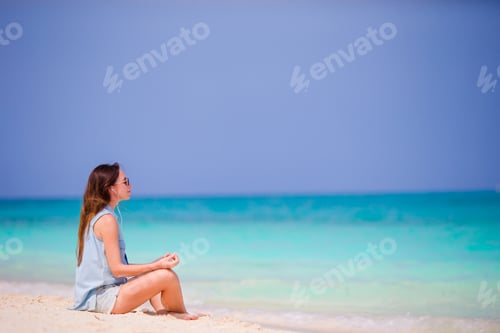 Preview: Beautiful woman in a meditation on the beach. Happy girl in yoga position relaxing on tropical beach