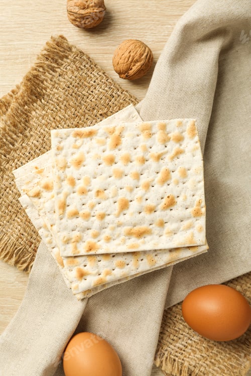 Preview: Matzo, eggs and nuts on towel on light wooden background, top view