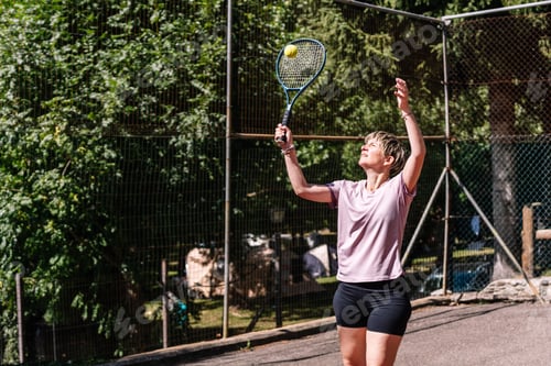 Preview: Woman serving tennis ball on sunny day