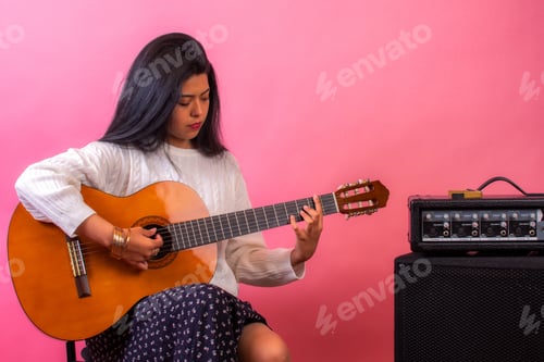 Visualização: Linda mulher latina tocando violão com uma parede rosa no fundo