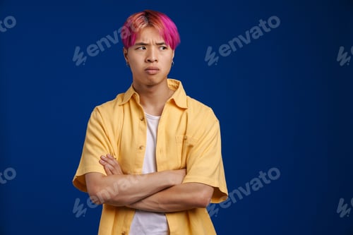 Preview: Asian boy with pink hair frowning and looking aside