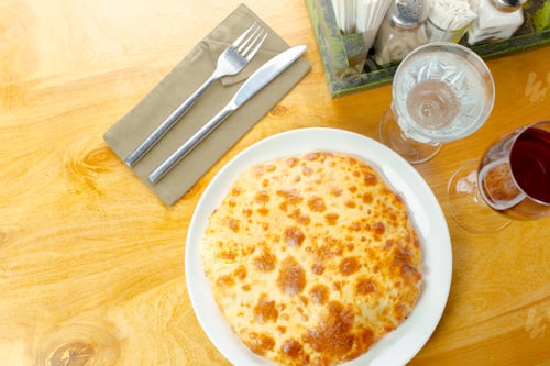 Preview: Delicious cheese pie served on a wooden table with cutlery and beverages nearby