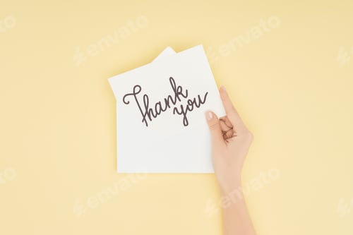 Preview: cropped person holding white postcard with thank you lettering isolated on yellow background