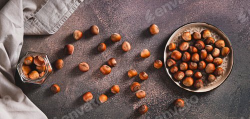 Preview: Nutritious hazelnuts on a plate and in a jar on the table top view web banner