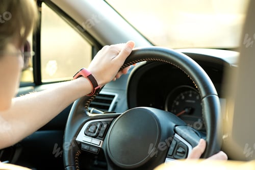 Preview: Close up view of woman holding steering wheel driving a car on city street on sunny day