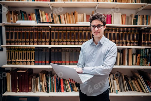 Preview: Young caucasian man indoor library standing using computer