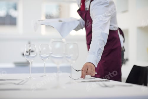 Preview: Waiter laying table in restaurant, mid section