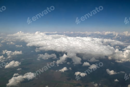 Preview: Aerial view from airplane window of white puffy clouds on bright sunny day.
