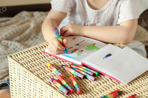 Preview: Little girl 6 years old draws with wax crayons in a sketch book