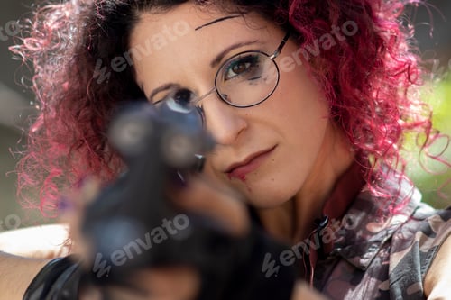 Preview: Young girl with pink hair and glasses holding a gun