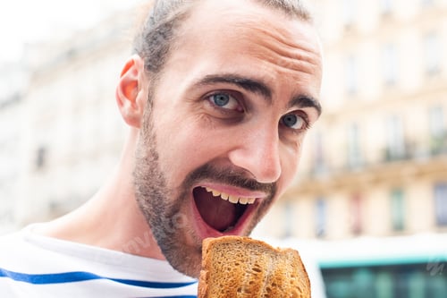 Preview: Close up young man eating sandwich outside in city
