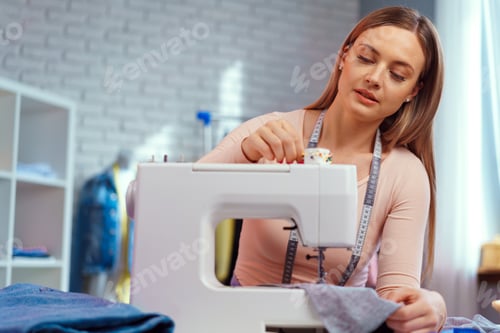 Preview: Young seamstress working on her sewing machine on textile factory