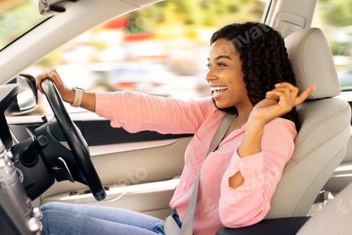 Preview: Happy black woman enjoying music driving luxury car