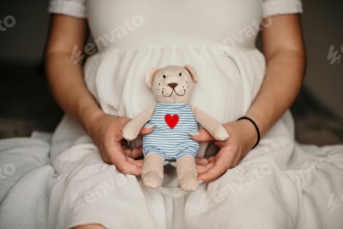 Preview: Pregnant female holding a toy bear in front of her belly