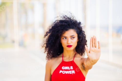 Preview: fearless brazilian woman in red bra with text girls power showing stop gesture at summer street