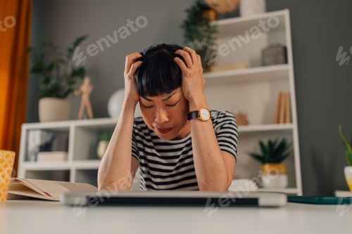 Preview: Asian woman feeling stressed at work, hands on head in frustration.