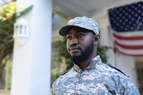 Preview: Portrait of african american male soldier standing in front of american flag outside home