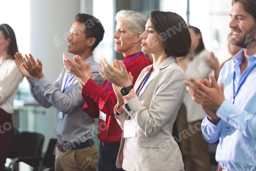 Preview: Side view of diverse business people applauding standing in a business seminar in office building