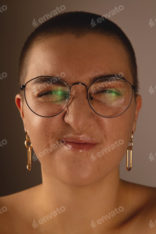 Preview: A swarthy girl with short hair and freckles in glasses grimaces and wrinkles the nose. Authentic