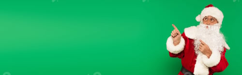 Preview: Santa claus in eyeglasses and costume pointing with fingers isolated on green, banner