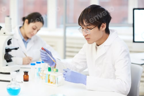 Preview: Young lab technician using pipette