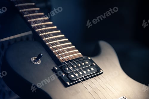 Preview: Close-up, black electric guitar on a dark background.