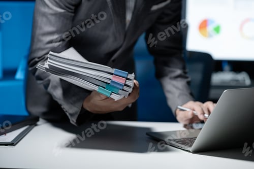 Preview: Employee checking important details of document on laptop, Documents were stacked on the desk, A bus