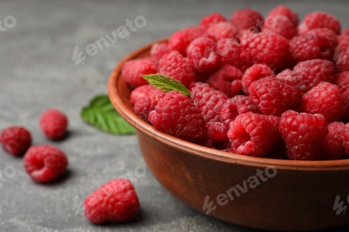 Preview: Bowl with delicious ripe raspberries on stone surface, closeup. Space for text