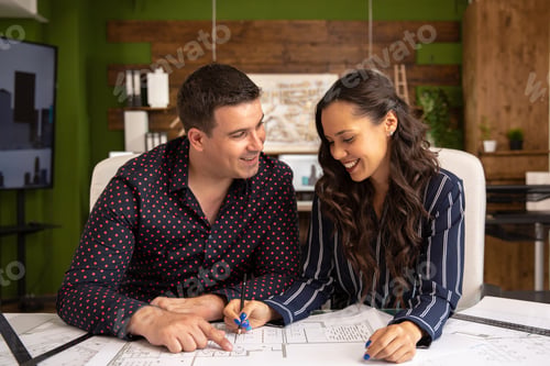 Preview: Two smiling architects sit at a table and put to the last details of the project