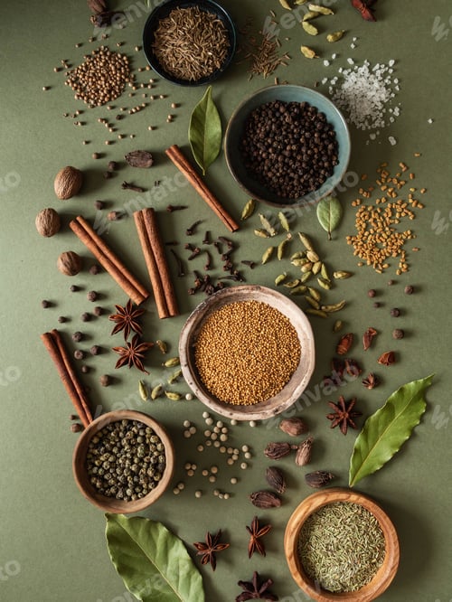 Preview: Various dry spices in small bowls and scattered on green background