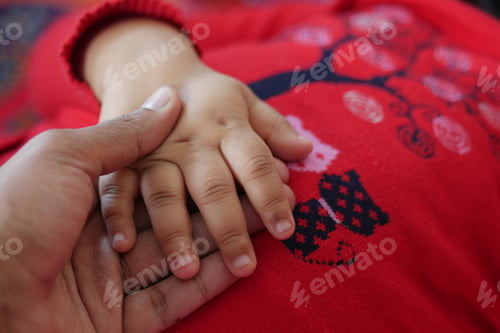 Preview: father holding hand of baby child, close up .