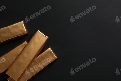 Preview: Chocolates in golden foil on black background, space for text