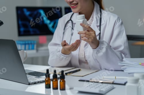 Visualização: Médica sorridente mostrando frasco de remédio durante consulta médica on-line usando laptop, sitti