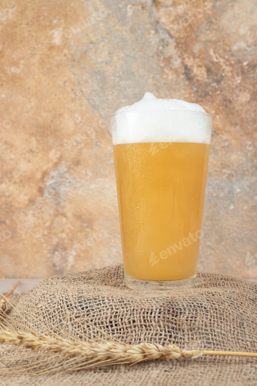 Preview: Glass of foamy beer on burlap wheat