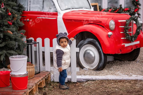 Preview: Toddler girl in Cozy Outfit by Festive Red Vintage Truck and Fence