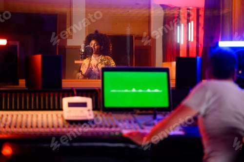 Preview: Talented multicultural singer recording in vocal isolation booth in music studio.