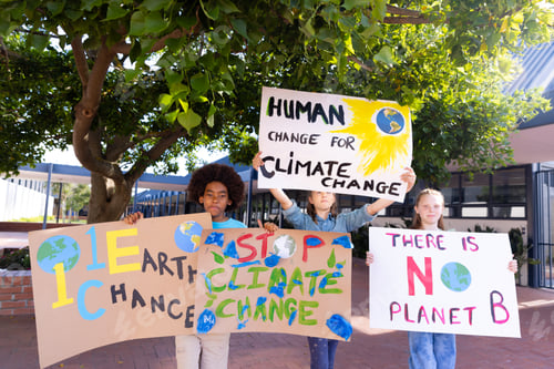 Preview: Happy diverse schoolchildren holding ecology posters made in art class outside school