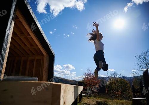 Preview: Woman on terrace at unfinished wooden frame house.